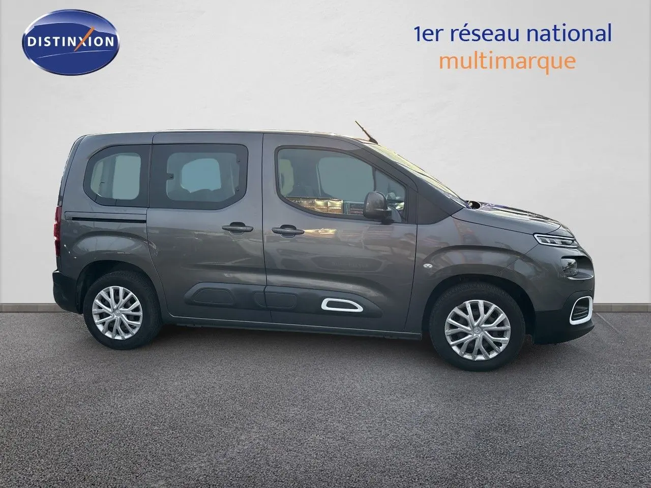 Vue de profil côté gauche d'un Citroën Berlingo Multispace gris platinium avec jantes alliage et protections latérales blanches.
