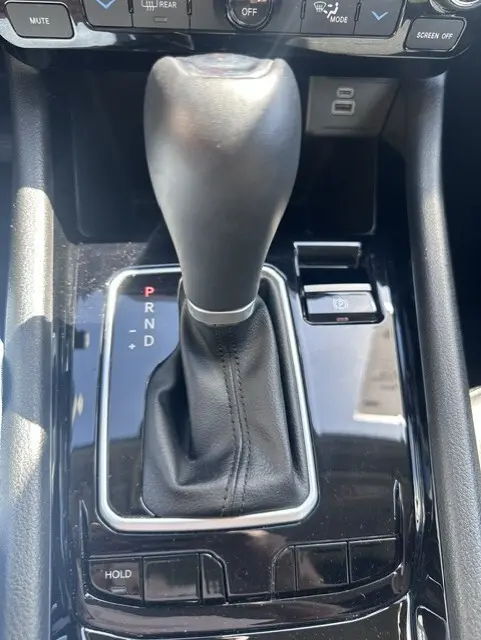 Gros plan sur le levier de vitesses automatique noir de la Jeep Compass 2025 avec bouton frein à main électronique et prises USB.