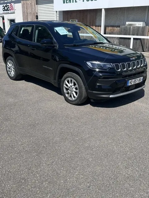 Jeep Compass noir vue 3/4 avant droit, jantes alliage 18 pouces, calandre distinctive à sept fentes, stationné en extérieur.