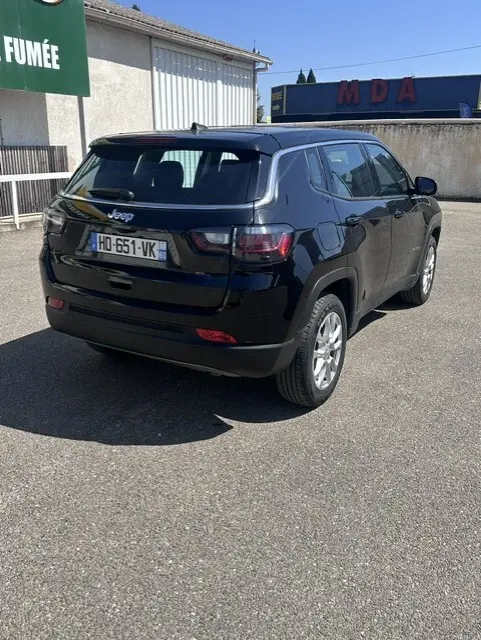 Jeep Compass noir vue 3/4 arrière droit, jantes alliage 18 pouces, stationné en extérieur sous soleil.
