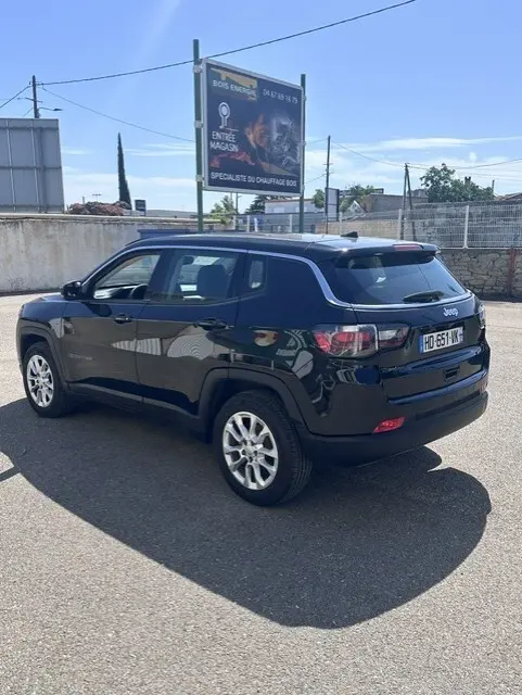 Vue 3/4 arrière droite d'un Jeep Compass noir 2025 avec jantes alliage 18 pouces, sur parking en extérieur.