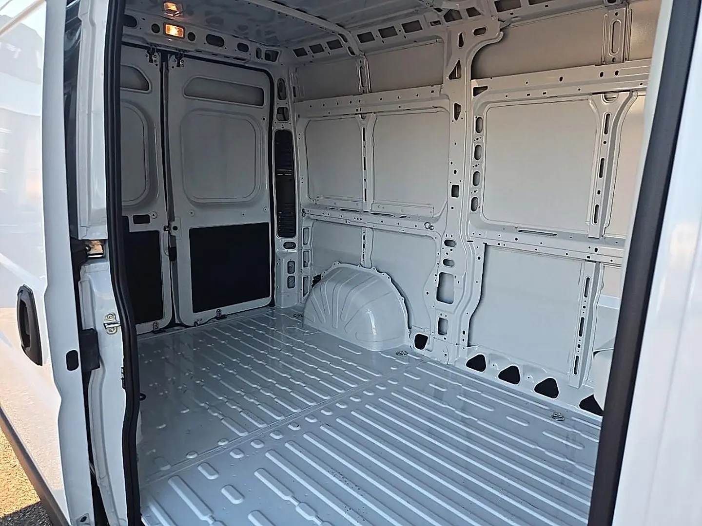 Intérieur vide du fourgon Peugeot Boxer blanc, vue en plongée depuis la porte latérale ouverte côté droit.