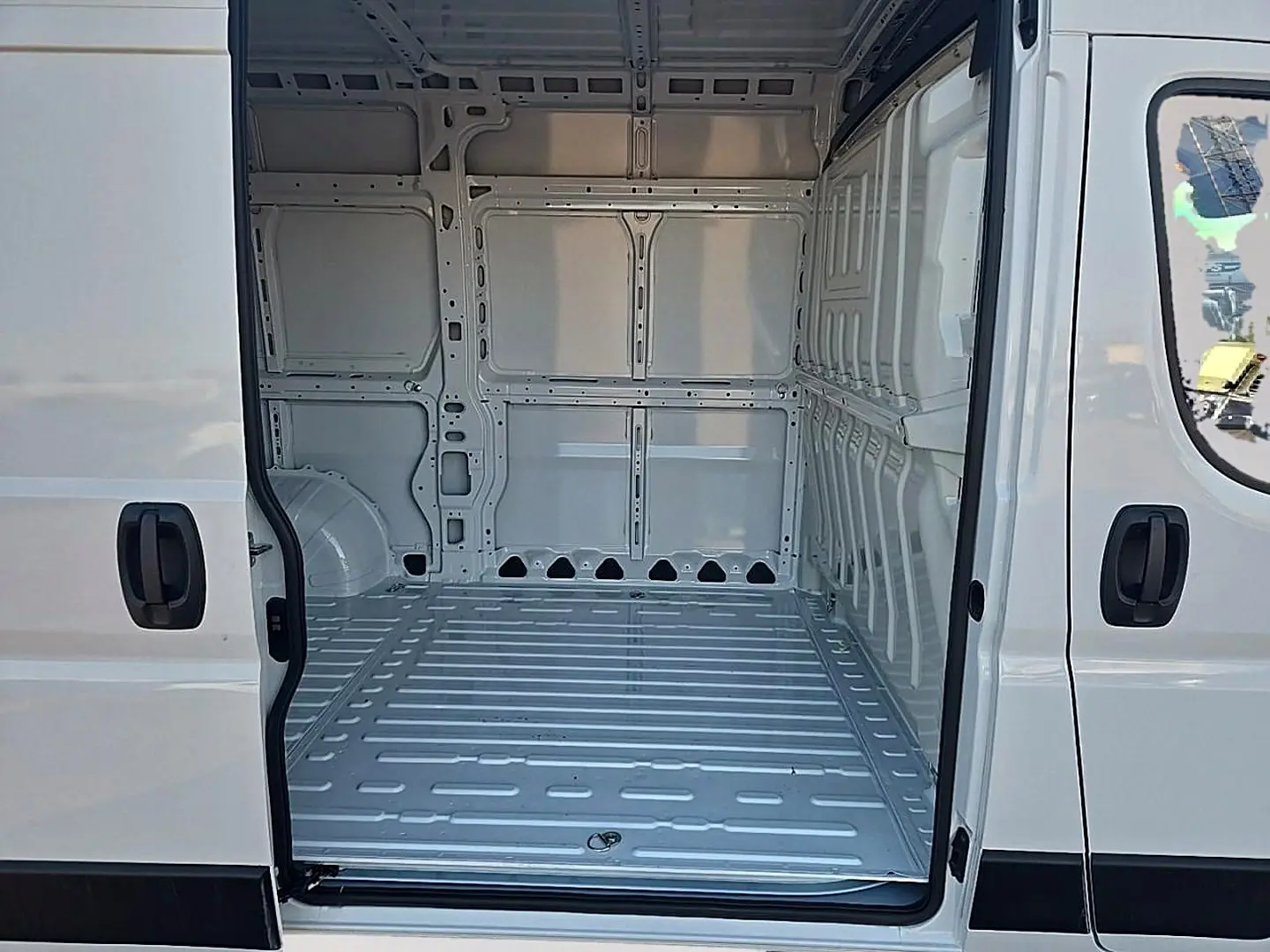 Vue intérieure du fourgon Peugeot Boxer blanc, montrant l'espace de chargement avec porte latérale coulissante ouverte.