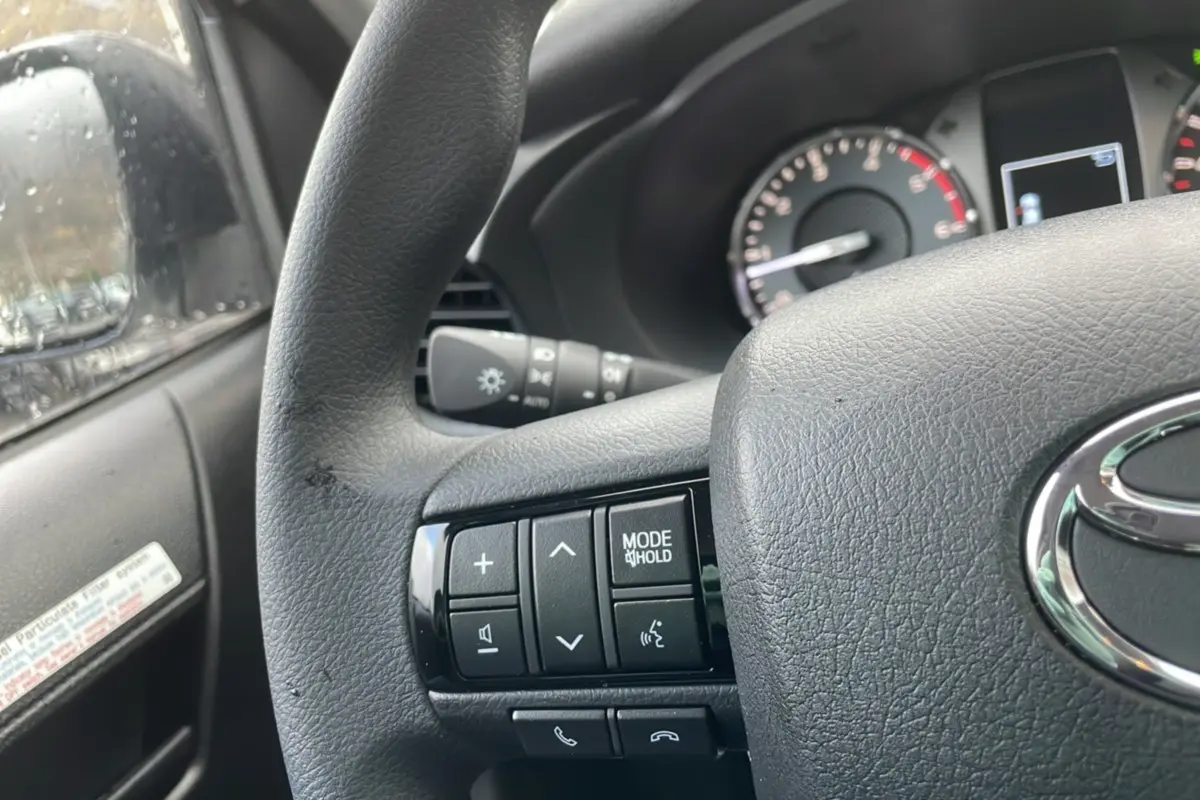 Vue rapprochée du volant noir du Toyota Hilux 2024, avec commandes multifonctions et tableau de bord partiel visible.