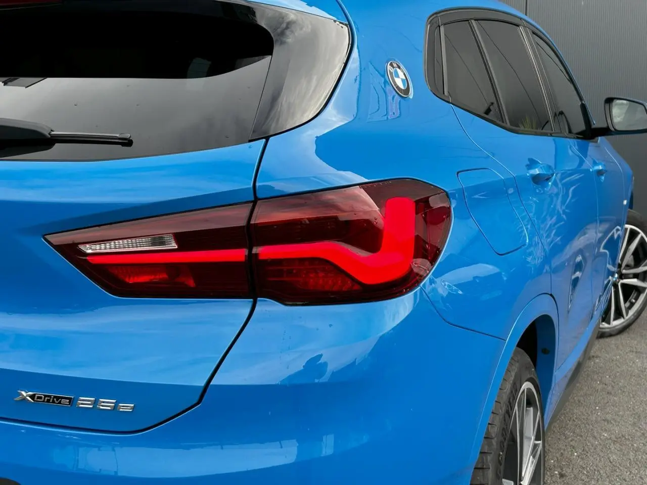 Vue 3/4 arrière droite d'une BMW X2 bleu Misano avec feux arrière LED et jantes alliage bicolores.
