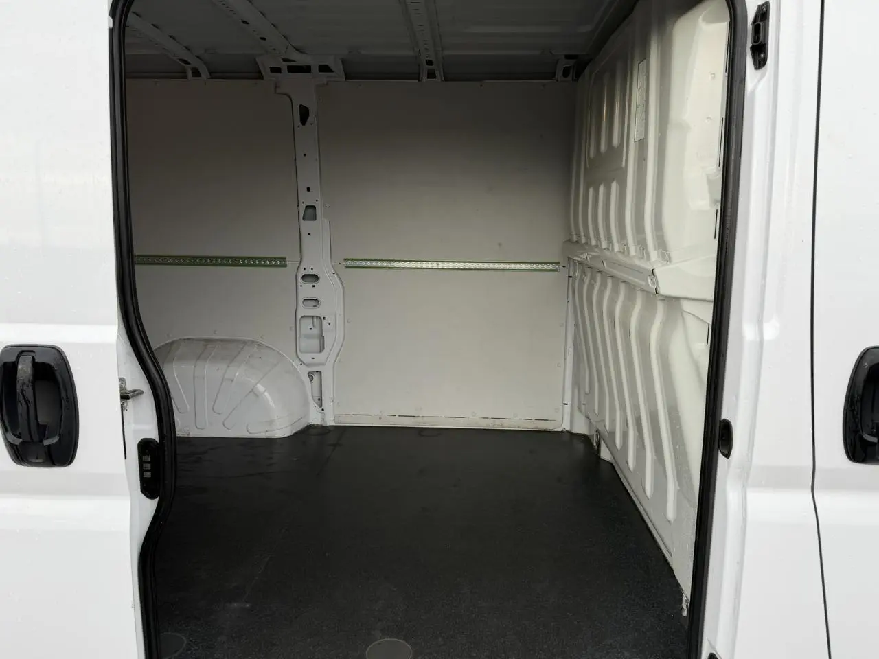 Vue intérieure du fourgon Opel Movano blanc, plancher bois visible avec portes latérales ouvertes.