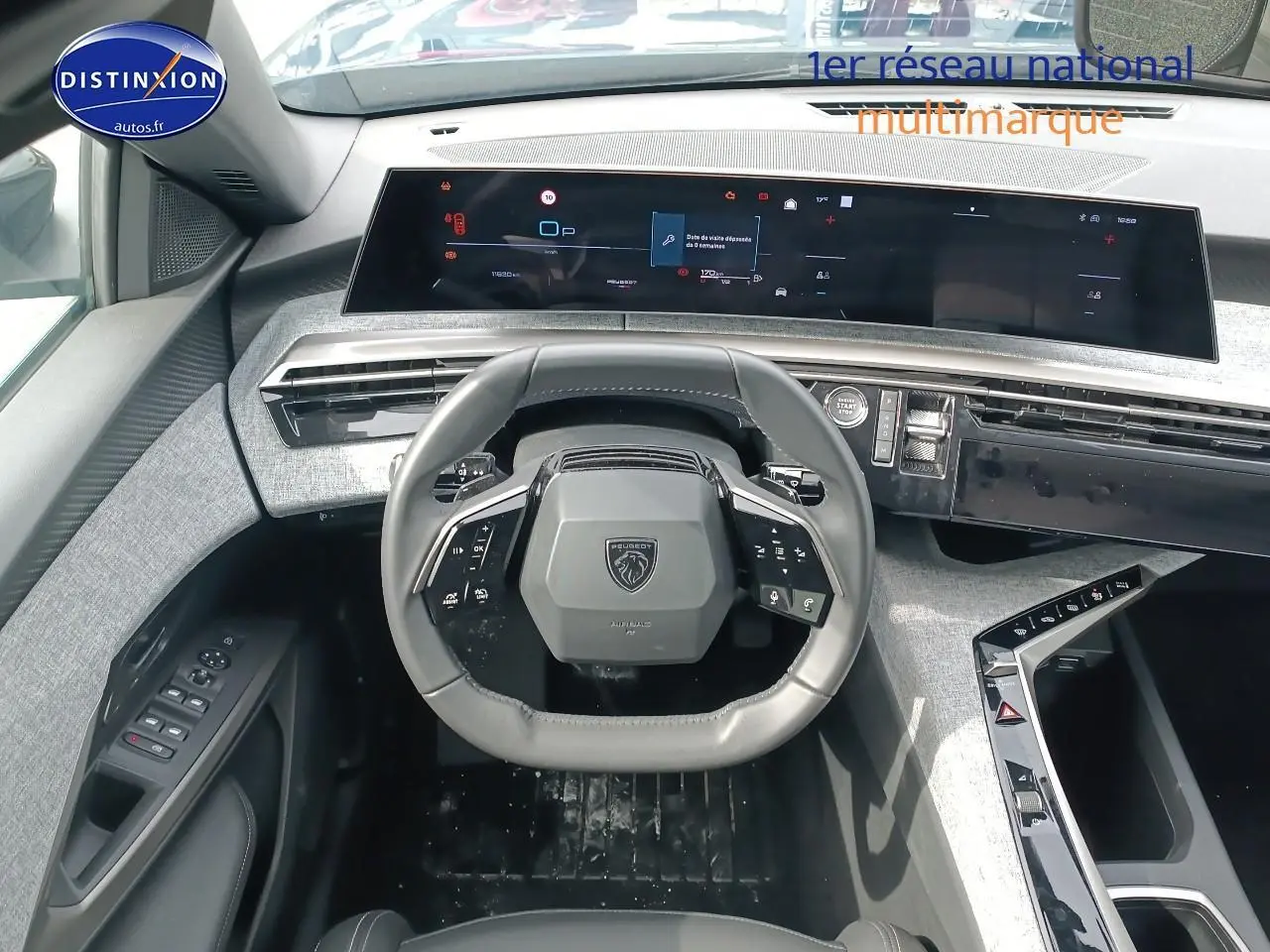 Vue intérieure frontale du tableau de bord et volant cuir noir du Peugeot 5008 Hybrid 145 allure 2025 avec écran tactile panoramique.