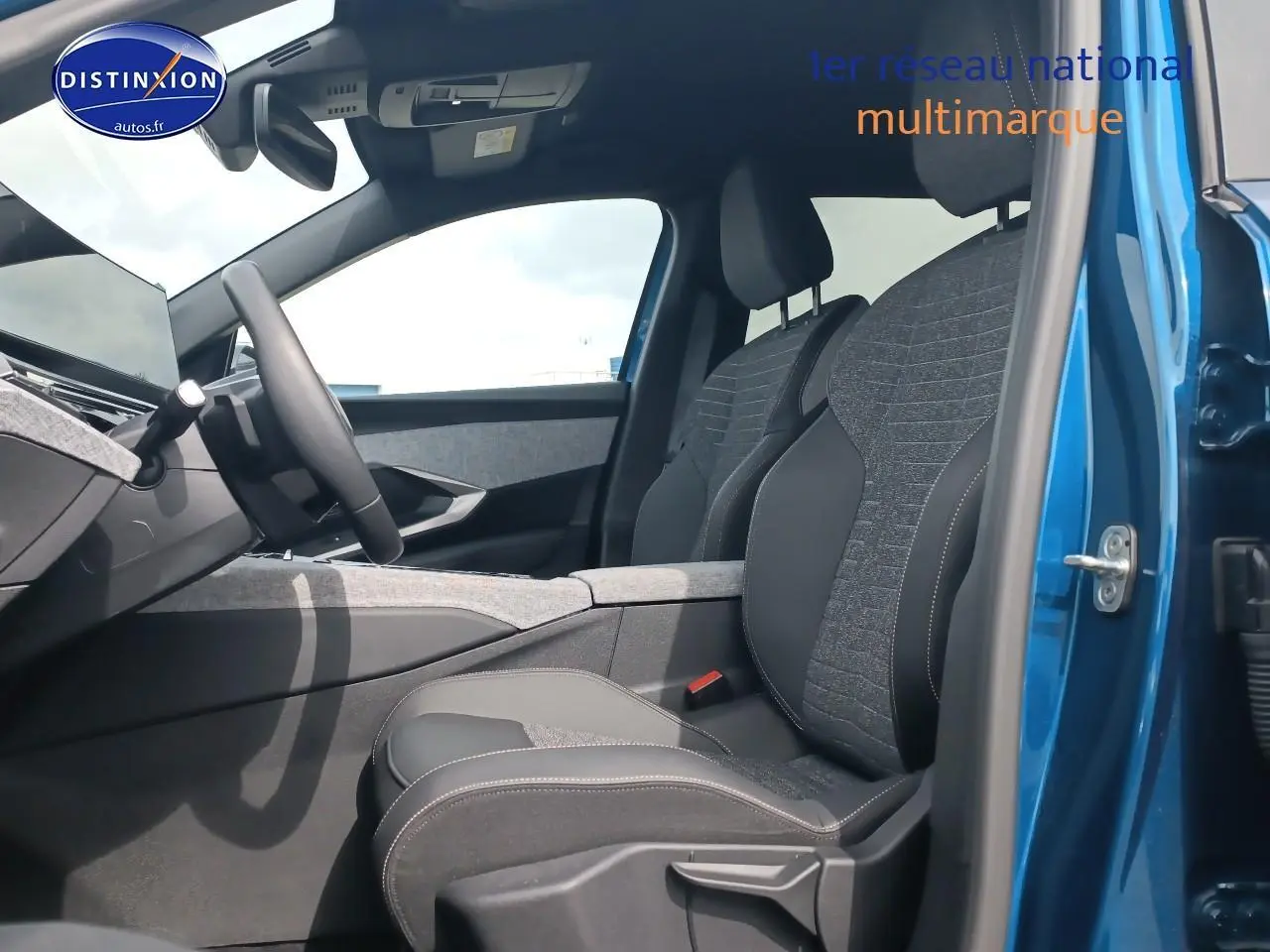 Intérieur avant du Peugeot 5008 bleu, vue côté conducteur avec sièges tissu et cuir gris, volant multifonction visible.
