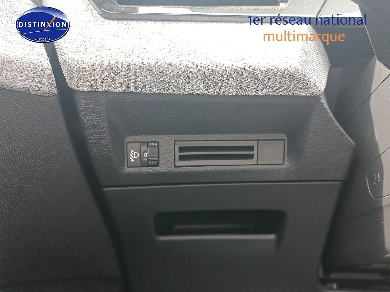 Détail de la console côté gauche avec commande de réglage des phares et tissu gris sur PEUGEOT 5008 bleu, vue intérieure.