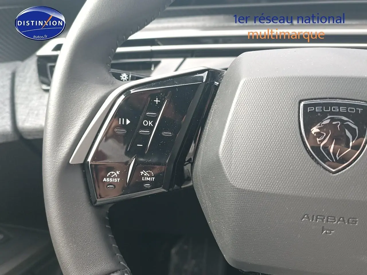 Gros plan sur le volant cuir multifonction gris avec logo Peugeot et commandes intégrées à gauche, intérieur du 5008 2025.