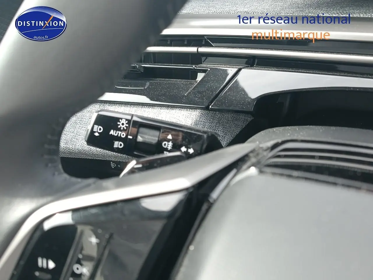 Gros plan sur la commande des phares et partie du volant cuir noir du Peugeot 5008 Hybrid 145 allure 2025.