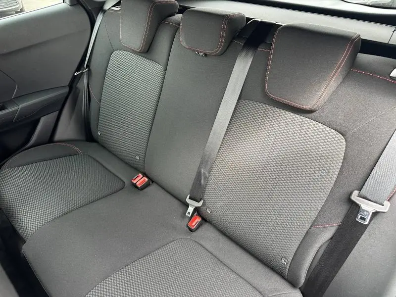 Vue intérieure de la banquette arrière du Ford Puma 2024 en tissu noir avec surpiqûres rouges et ceintures de sécurité visibles.