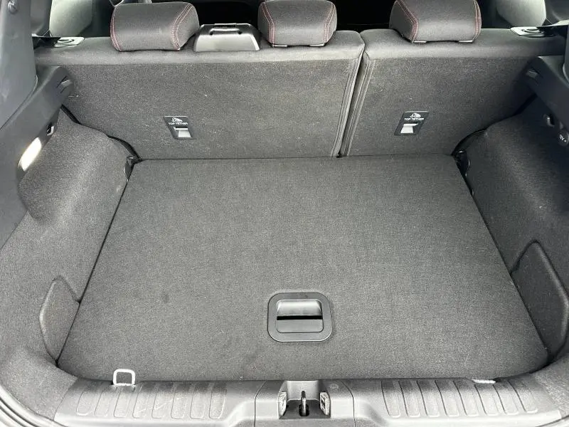 Vue intérieure du coffre spacieux du Ford Puma 2024, avec revêtement noir et sièges arrière rabattables au fond.