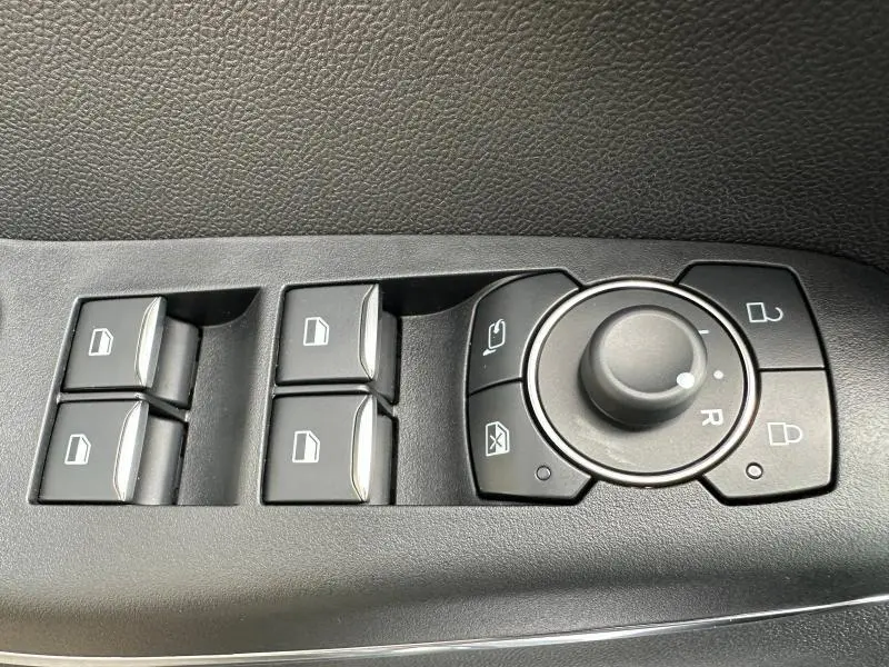 Commandes des vitres électriques et réglage des rétroviseurs sur la porte intérieure d'un Ford Puma 2024 noir Agate Métallisée.