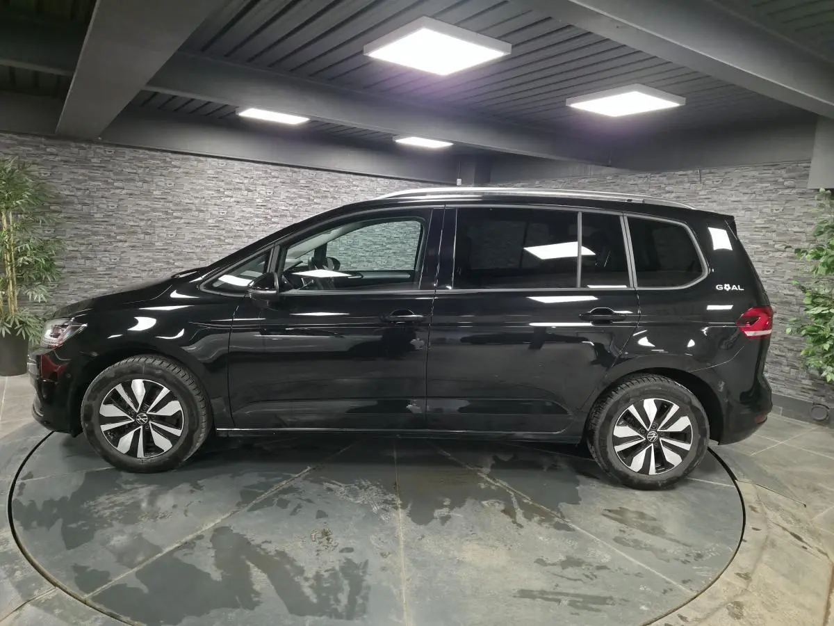Vue latérale droite d'un Volkswagen Touran noir nacré 2025 avec jantes alliage et badge GOAL à l'arrière.
