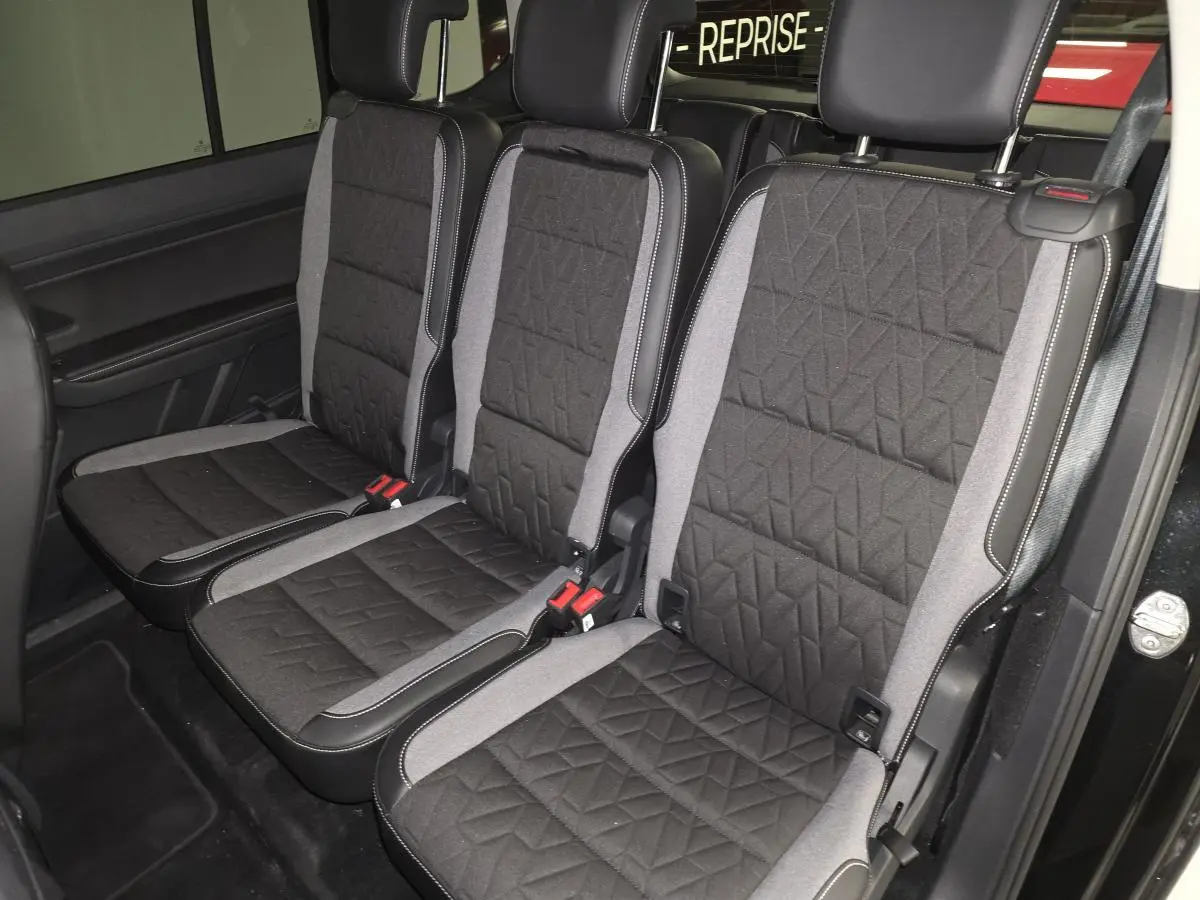 Vue intérieure des trois sièges individuels de la deuxième rangée du Volkswagen Touran noir, avec sellerie tissu Lasano noire et grise.