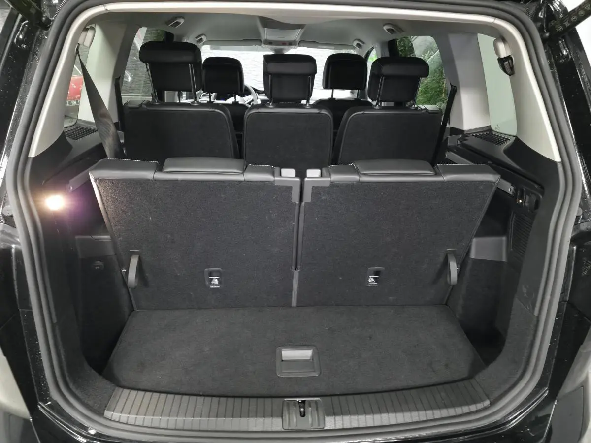 Coffre ouvert vu de l'arrière d'un Volkswagen Touran noir 7 places, sièges arrière en position verticale.
