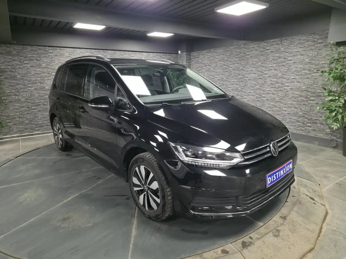 Volkswagen Touran noir en 3/4 avant droit, avec calandre chromée et jantes alliage distinctives.
