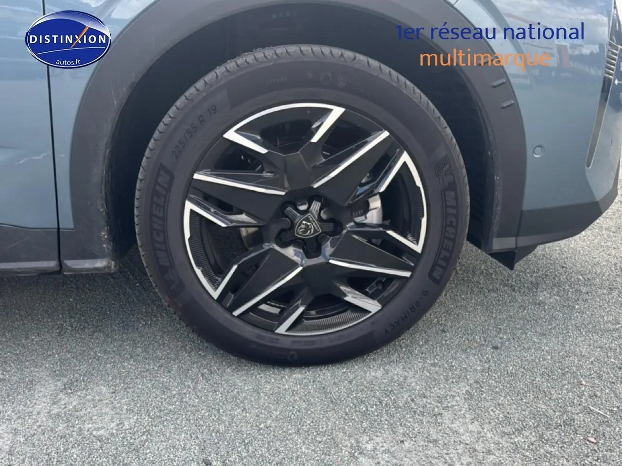 Gros plan sur la roue avant gauche avec jante alu noire et argentée du Peugeot 3008 bleu 2025.