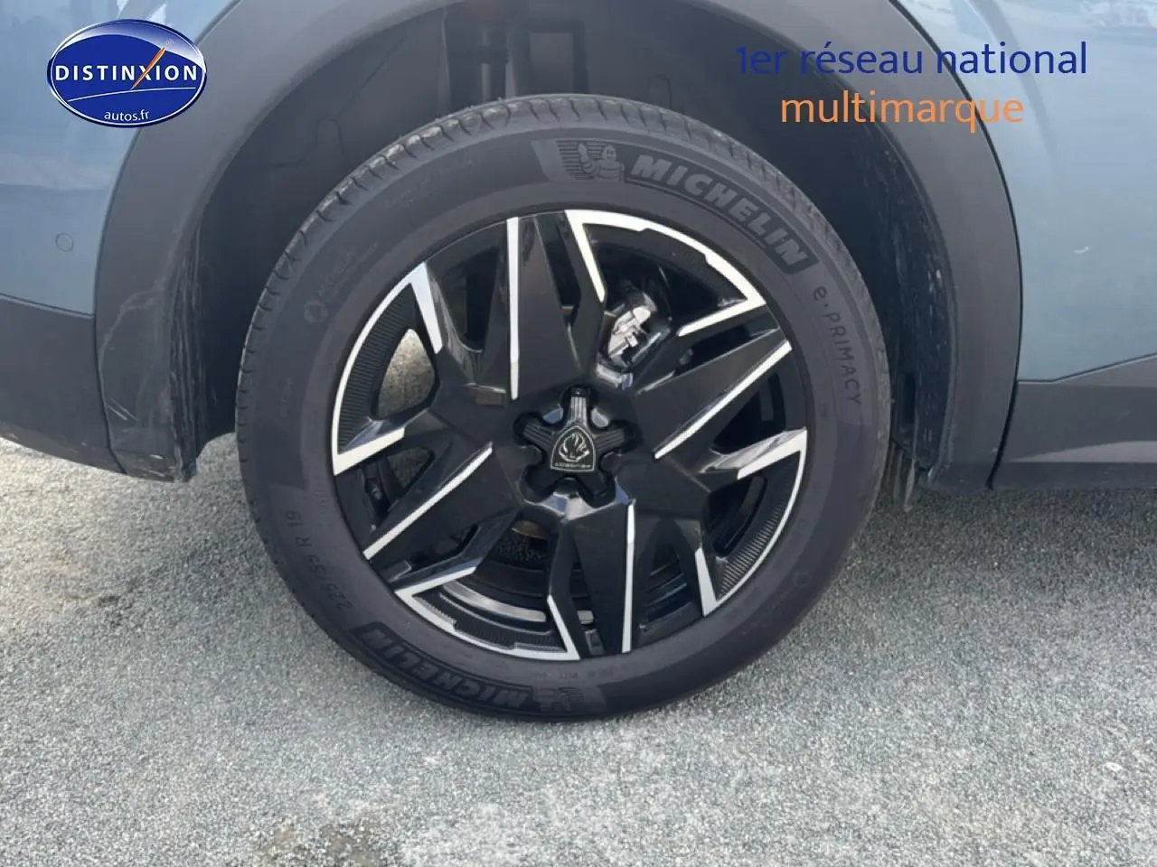 Gros plan sur la roue avant gauche avec jante alu noire et argentée du Peugeot 3008 bleu 2025.