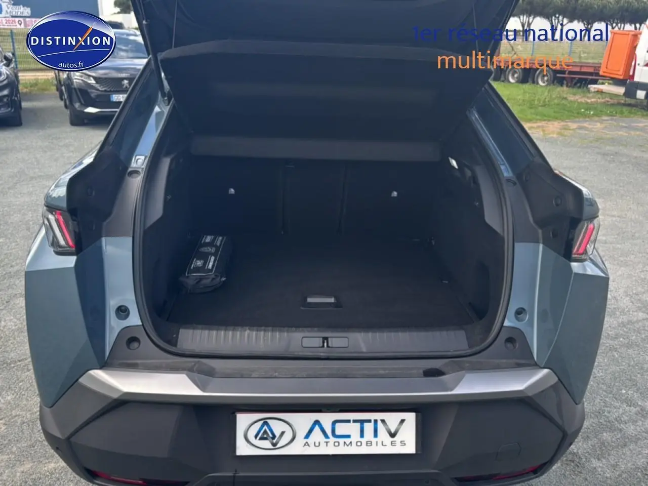 Coffre ouvert vue arrière d’un Peugeot 3008 bleu 2025, avec hayon levé et espace de chargement vide.
