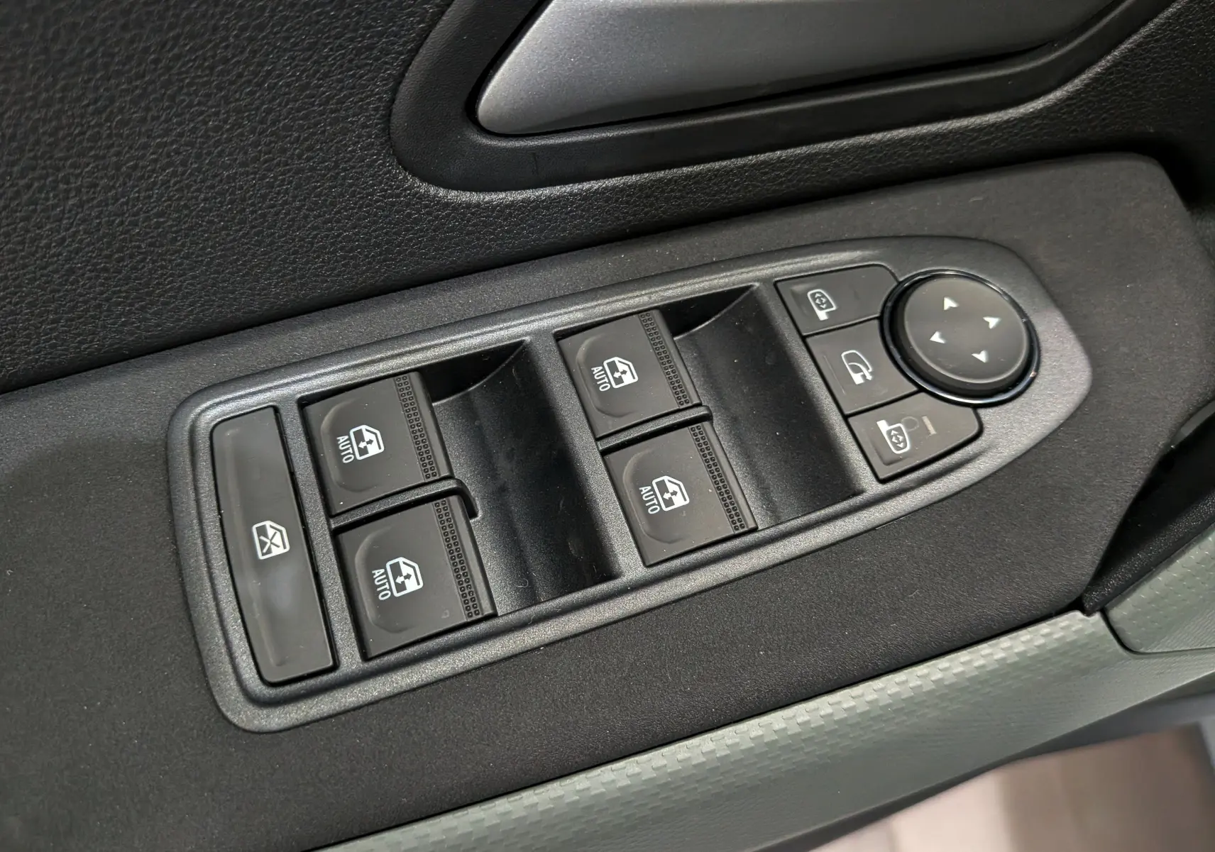 Gros plan sur les commandes des vitres électriques et des rétroviseurs du côté conducteur d'un Dacia Bigster blanc Glacier.