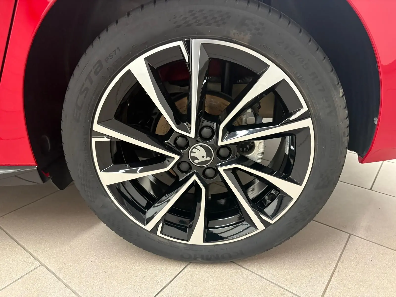 Gros plan sur la roue avant droite de la Skoda Fabia rouge Velvet avec jante noire et argentée au design moderne.