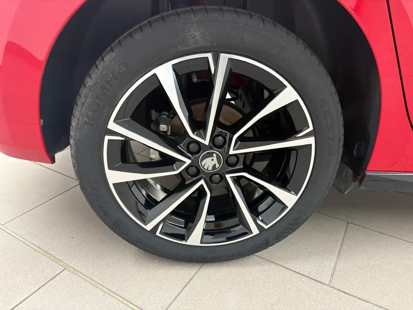 Gros plan sur la roue avant droite d'une Skoda Fabia rouge Velvet avec jante alliage noire et argentée.