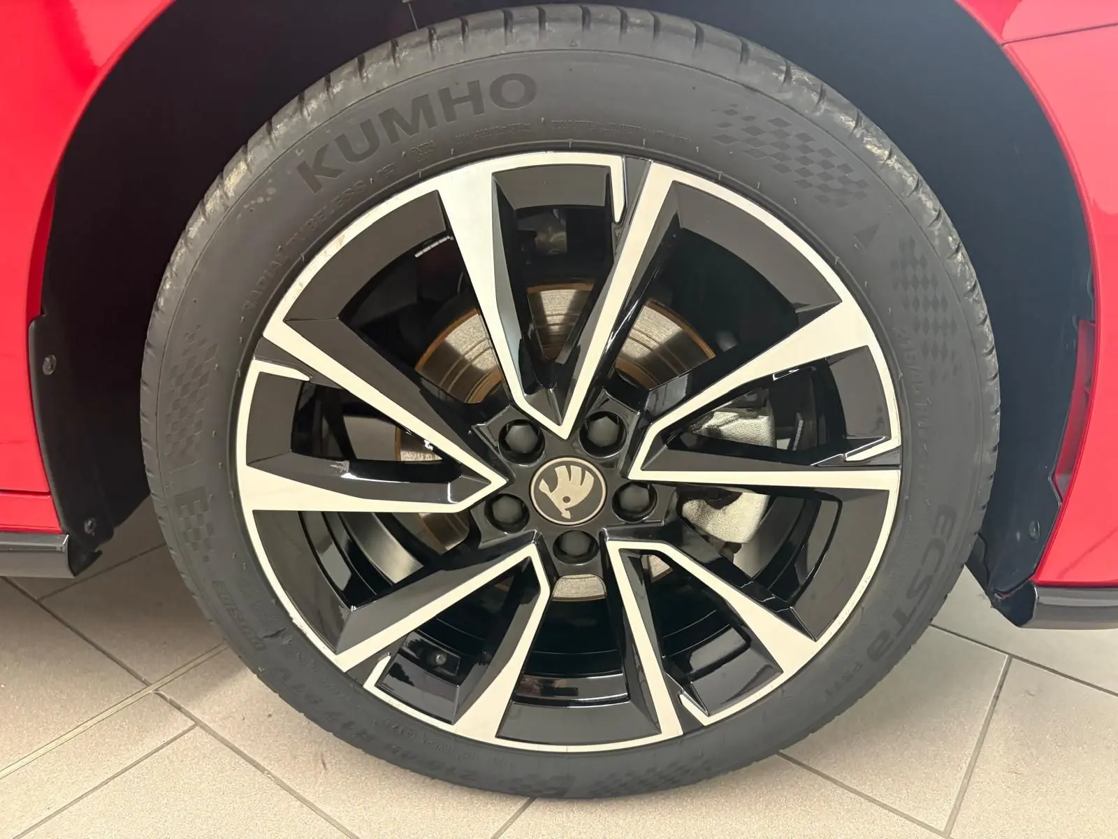 Gros plan sur la roue avant droite d’une Skoda Fabia rouge Velvet avec jante noire et argentée au design moderne.