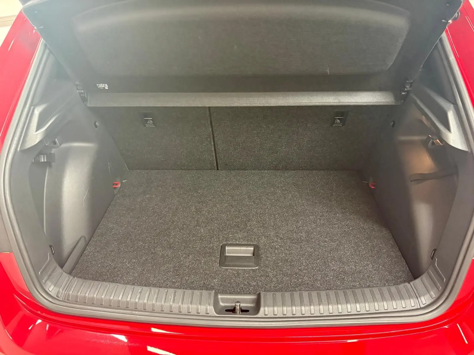 Coffre ouvert vu de l'arrière d'une Skoda Fabia rouge Velvet avec plancher plat et habillage intérieur noir.
