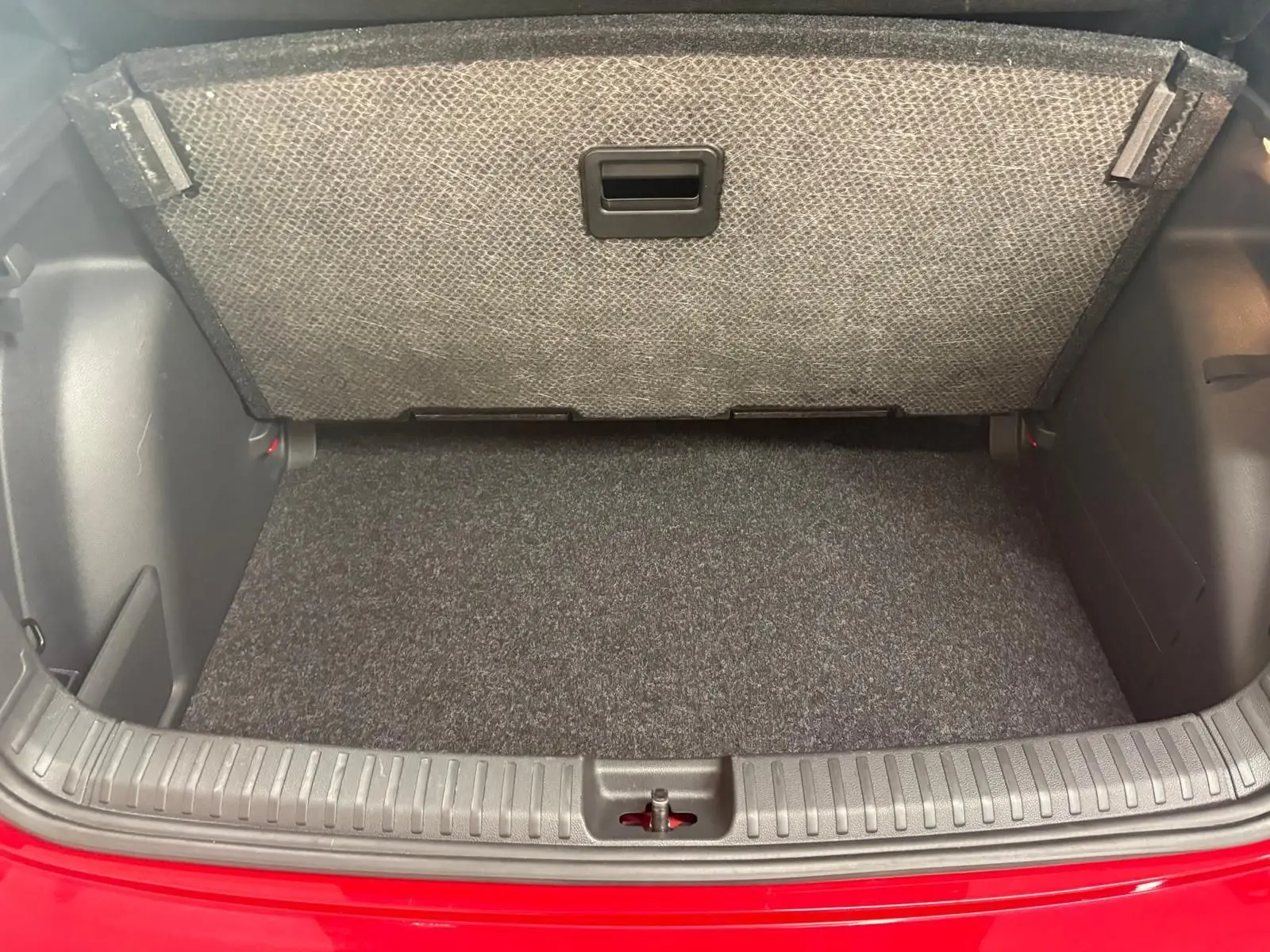 Coffre ouvert de la Skoda Fabia 2025 rouge Velvet avec double plancher variable visible au-dessus du tapis gris.