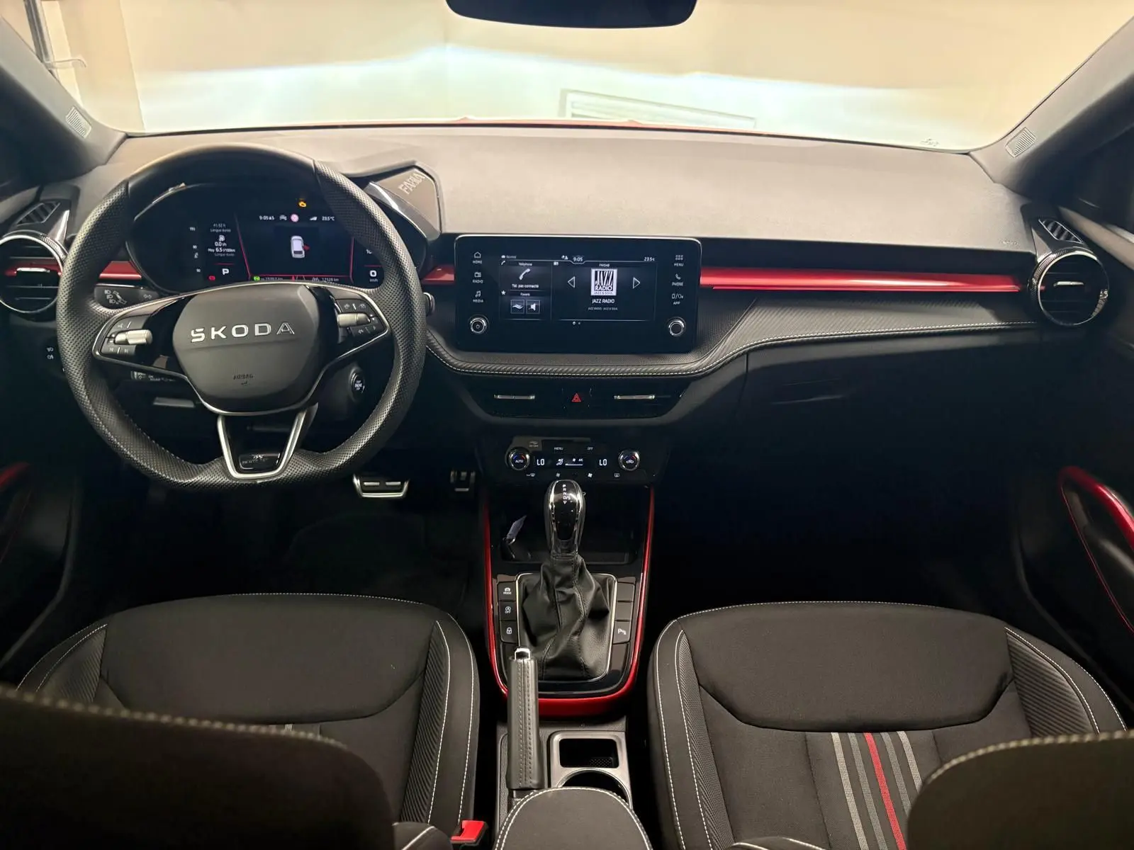 Vue intérieure avant de la Skoda Fabia Monte Carlo 2025, tableau de bord noir avec touches rouges et volant multifonction.