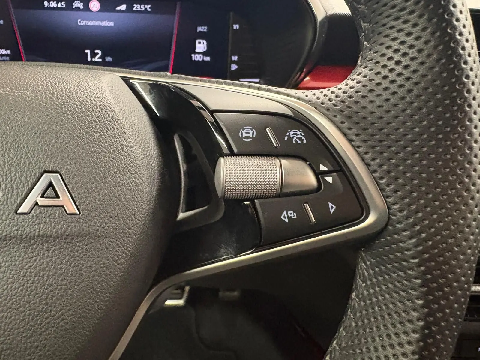 Gros plan sur les commandes à droite du volant perforé d’une Skoda Fabia 2025, avec affichage numérique en arrière-plan.