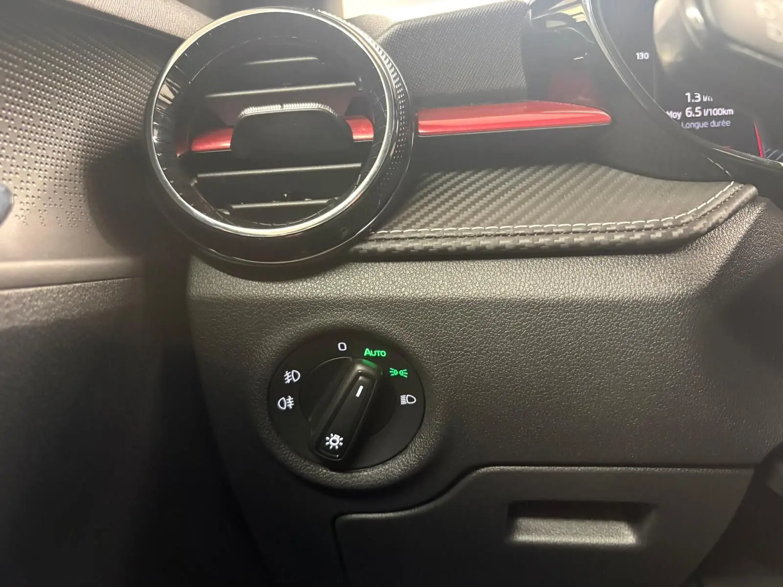 Détail du tableau de bord côté gauche de la Skoda Fabia 2025, avec aérateur rond et commande des phares en mode auto.