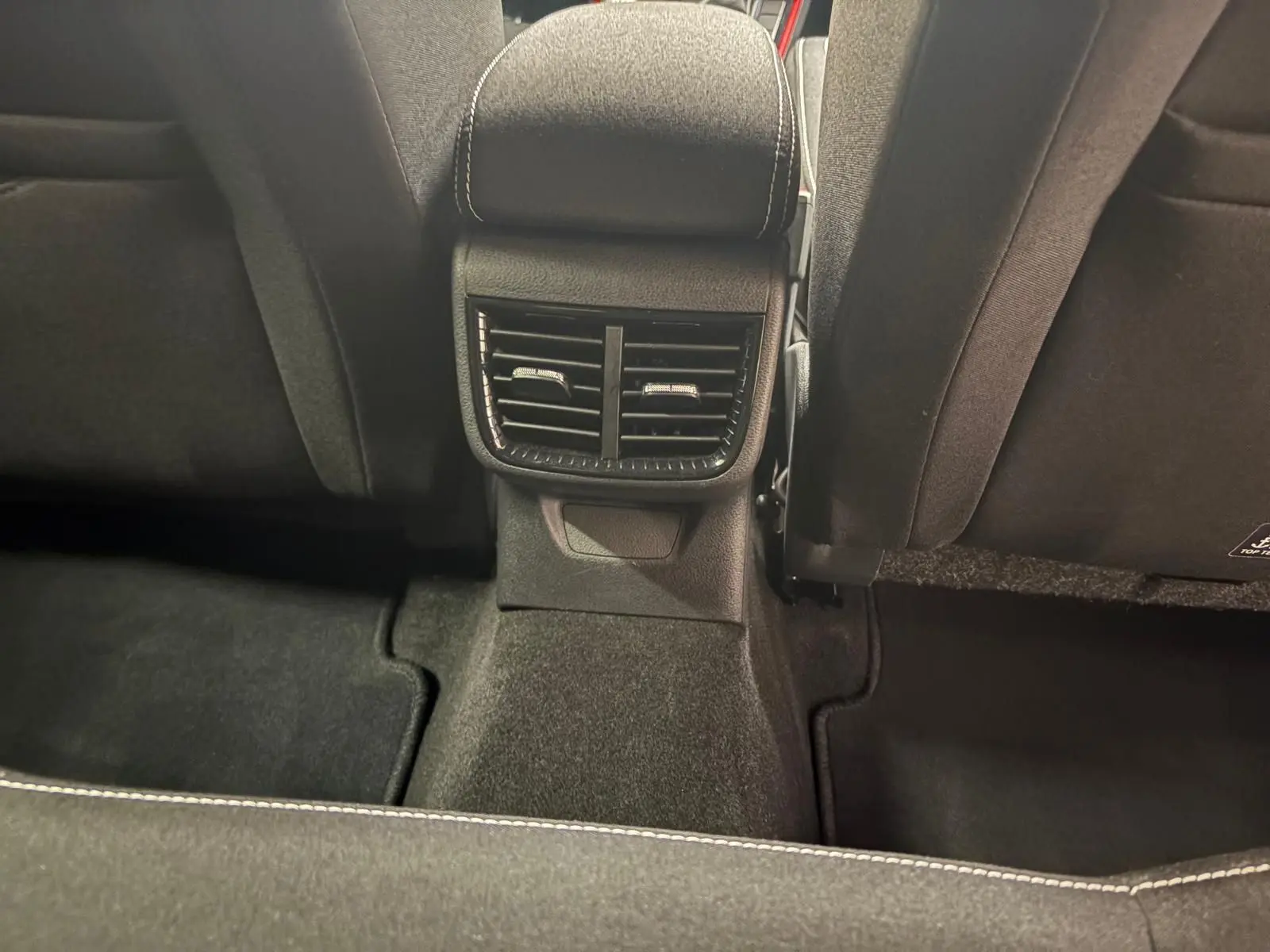 Vue rapprochée des aérateurs arrière et du tunnel central noir avec surpiqûres blanches dans une Skoda Fabia Monte Carlo 2025.