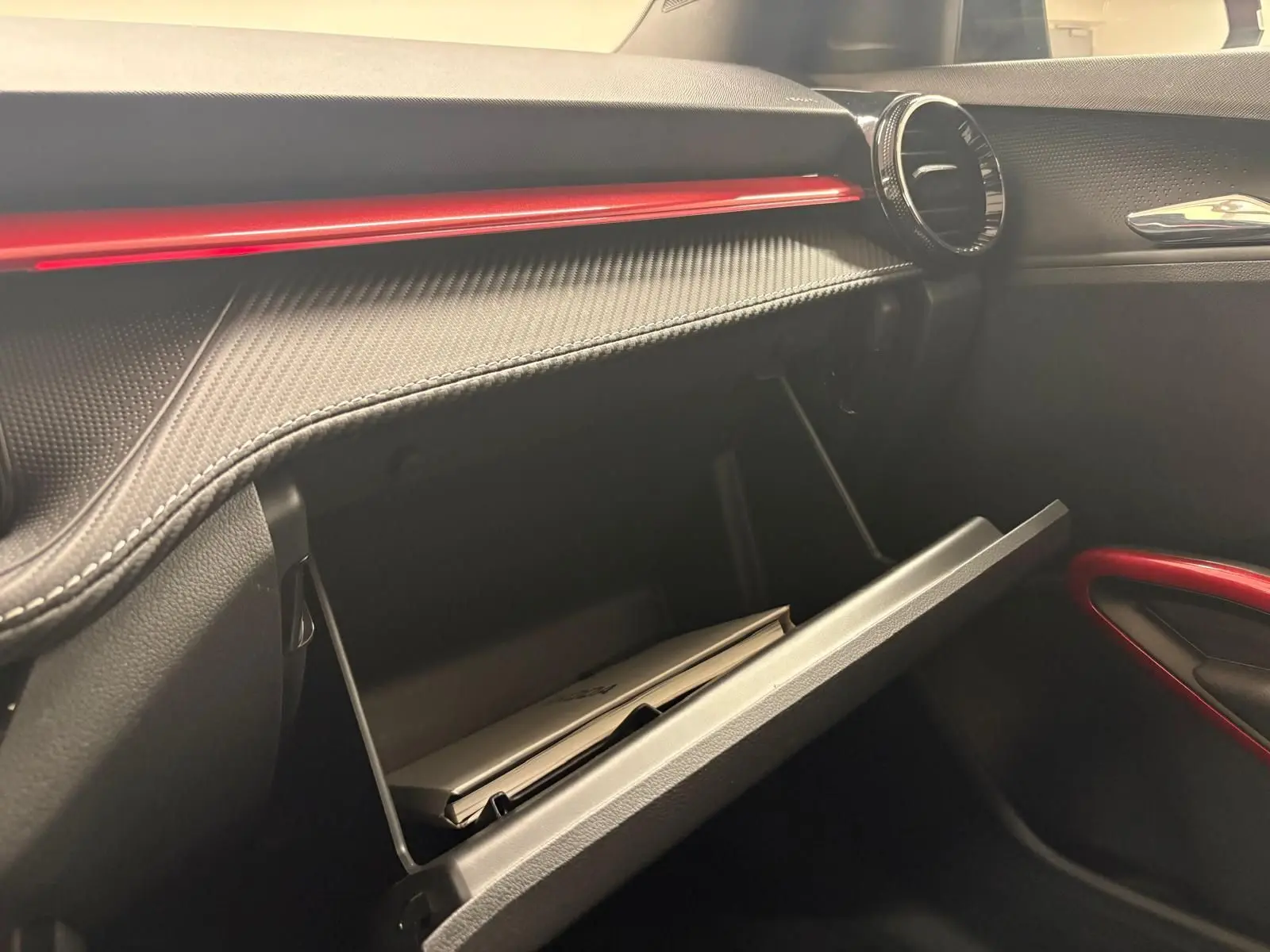 Vue intérieure côté passager de la boîte à gants ouverte d'une Skoda Fabia rouge velvet avec insert noir et détails rouges.