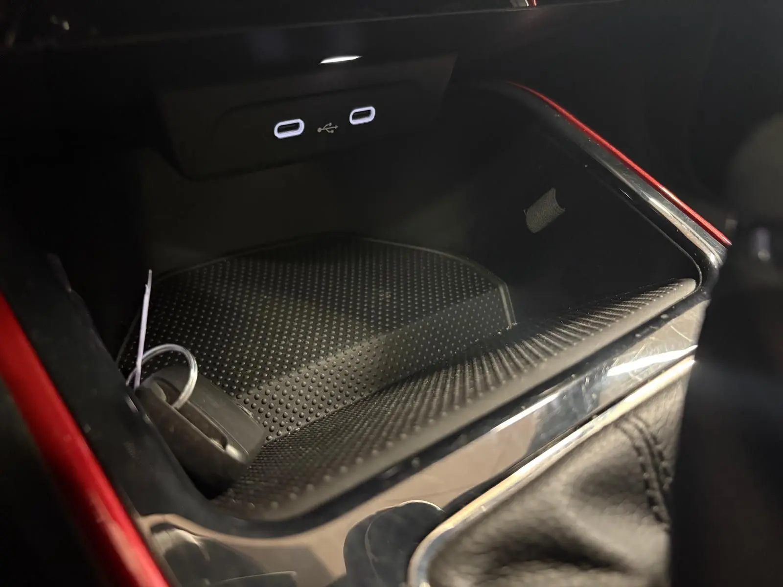 Gros plan sur la console centrale d’une Skoda Fabia rouge Velvet avec prise USB double et rangement intérieur noir.