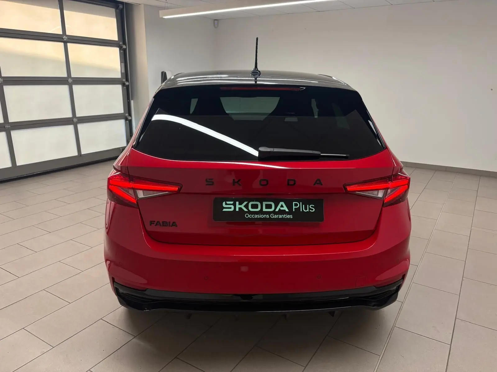 Vue arrière d'une Skoda Fabia 2025 rouge Velvet avec toit noir, en intérieur, mettant en valeur ses feux LED et son logo SKODA.