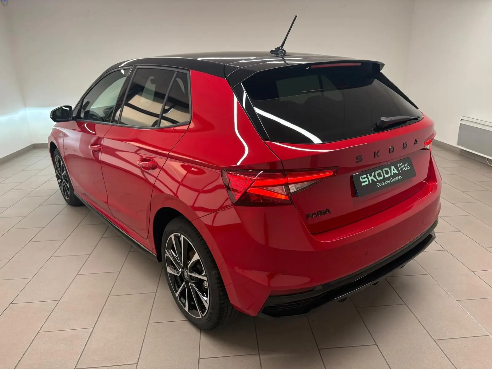 Vue 3/4 arrière droite d'une Skoda Fabia 2025 rouge velvet avec toit noir et jantes alliage noires.