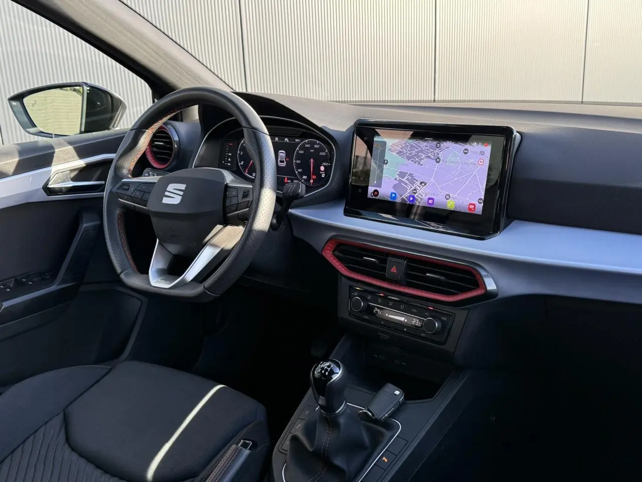 Intérieur SEAT Ibiza TSI 115 FR 2025 côté conducteur, volant cuir, écran tactile avec navigation et levier de vitesses manuel.