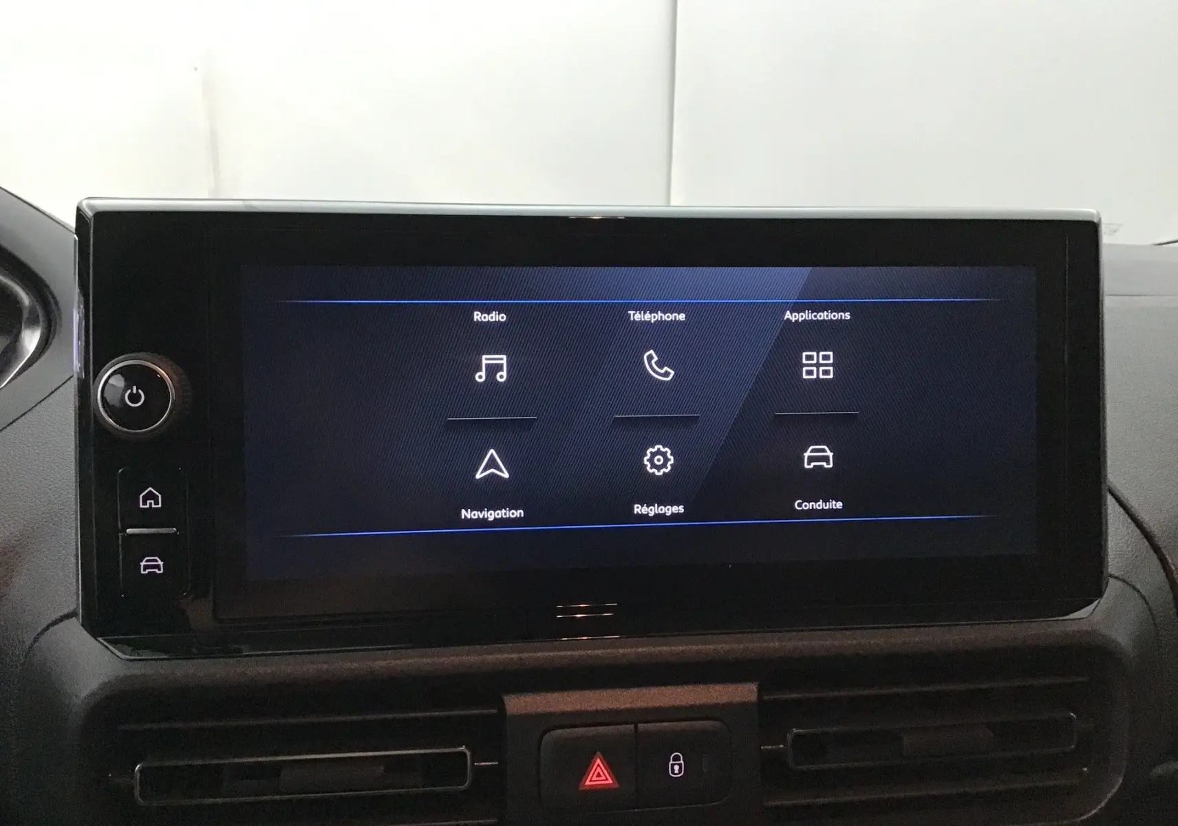 Écran tactile central du Peugeot Partner 2025 affichant les options radio, téléphone, navigation et réglages, intérieur noir.