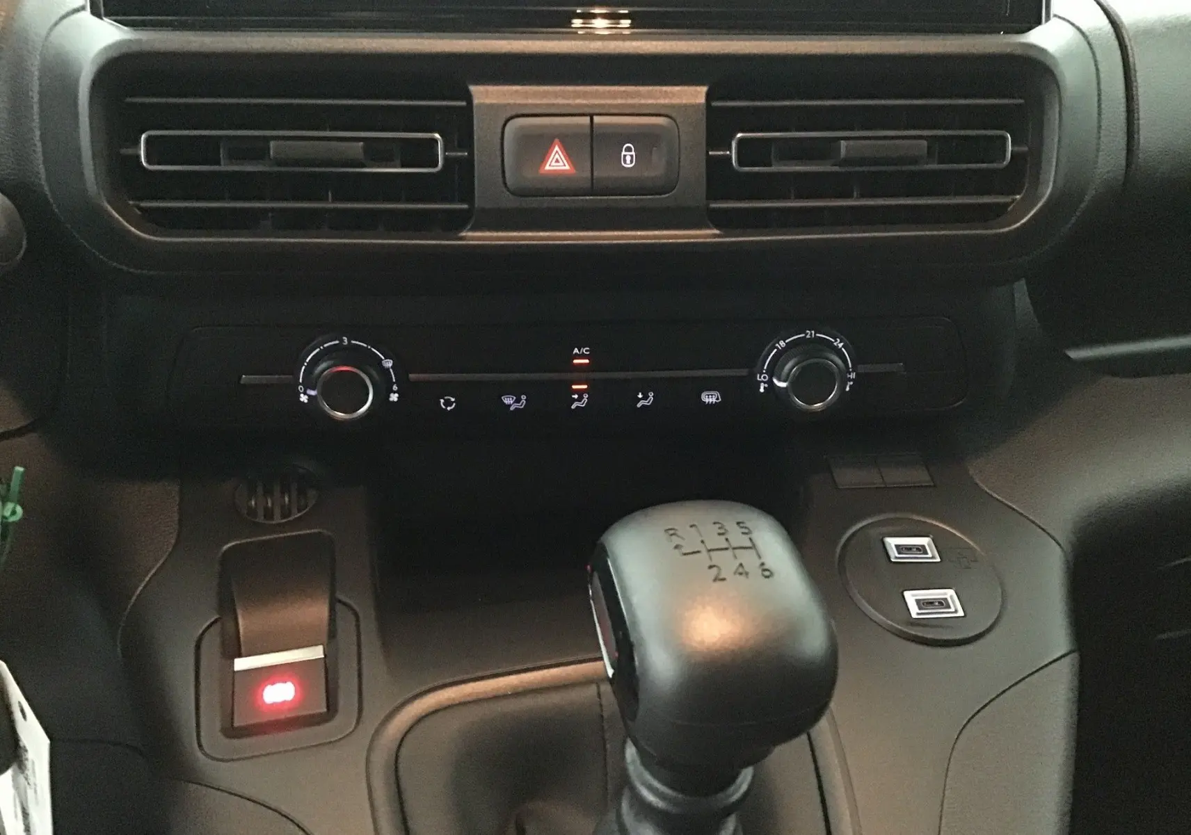 Vue rapprochée de la console centrale du Peugeot Partner 2025, avec levier de vitesses manuel et commandes de climatisation.