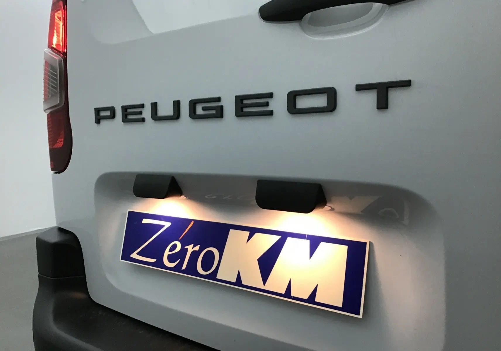 Vue rapprochée arrière gauche du Peugeot Partner blanc 2025 avec logo et plaque d’immatriculation éclairée Zéro KM.
