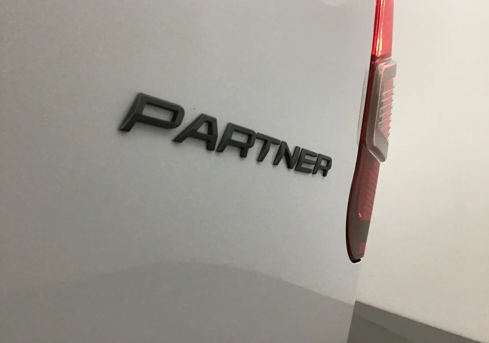 Détail arrière droit du Peugeot Partner blanc 2025 avec logo PARTNER et feu arrière vertical visible.
