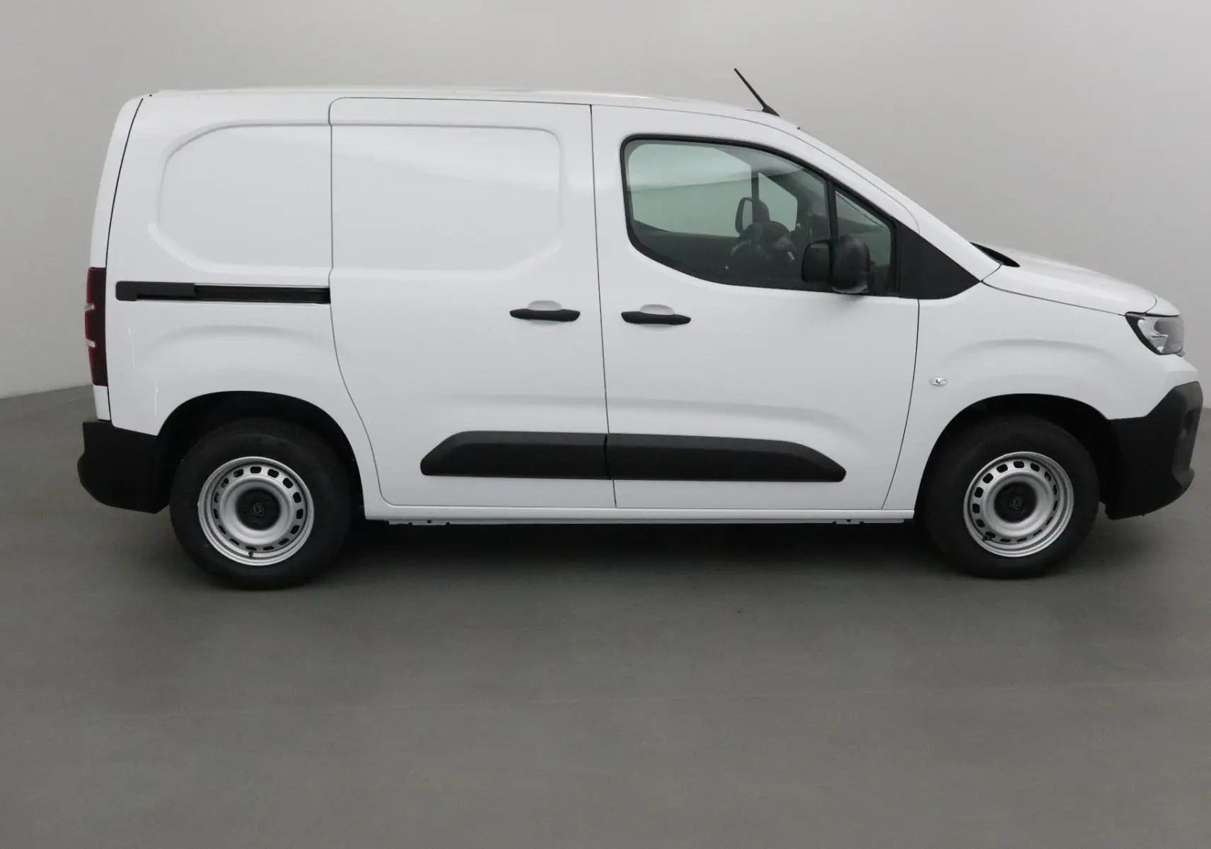 Peugeot Partner blanc vu de profil côté gauche, fourgonnette utilitaire avec protections noires sur les portières.
