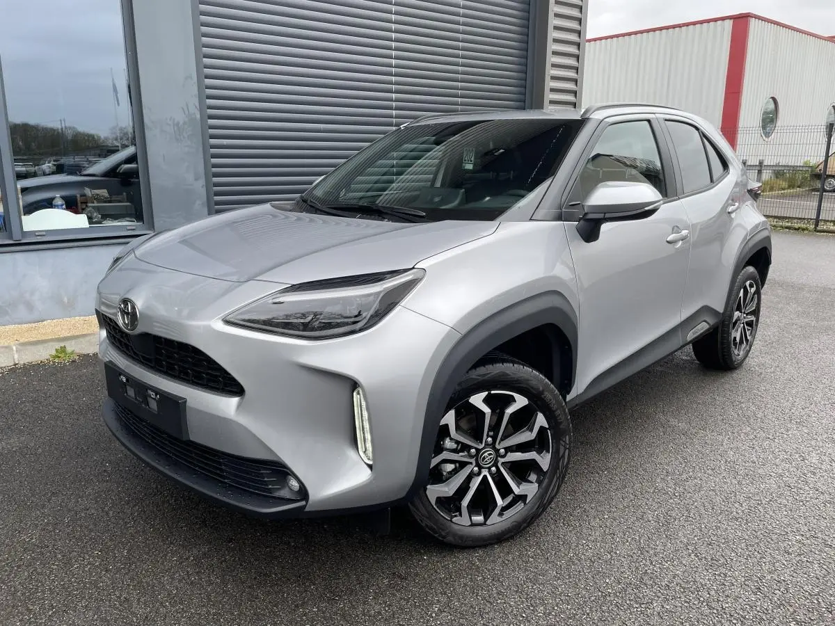 Toyota Yaris Cross gris clair vue 3/4 avant droit avec jantes noires et toit noir brillant.