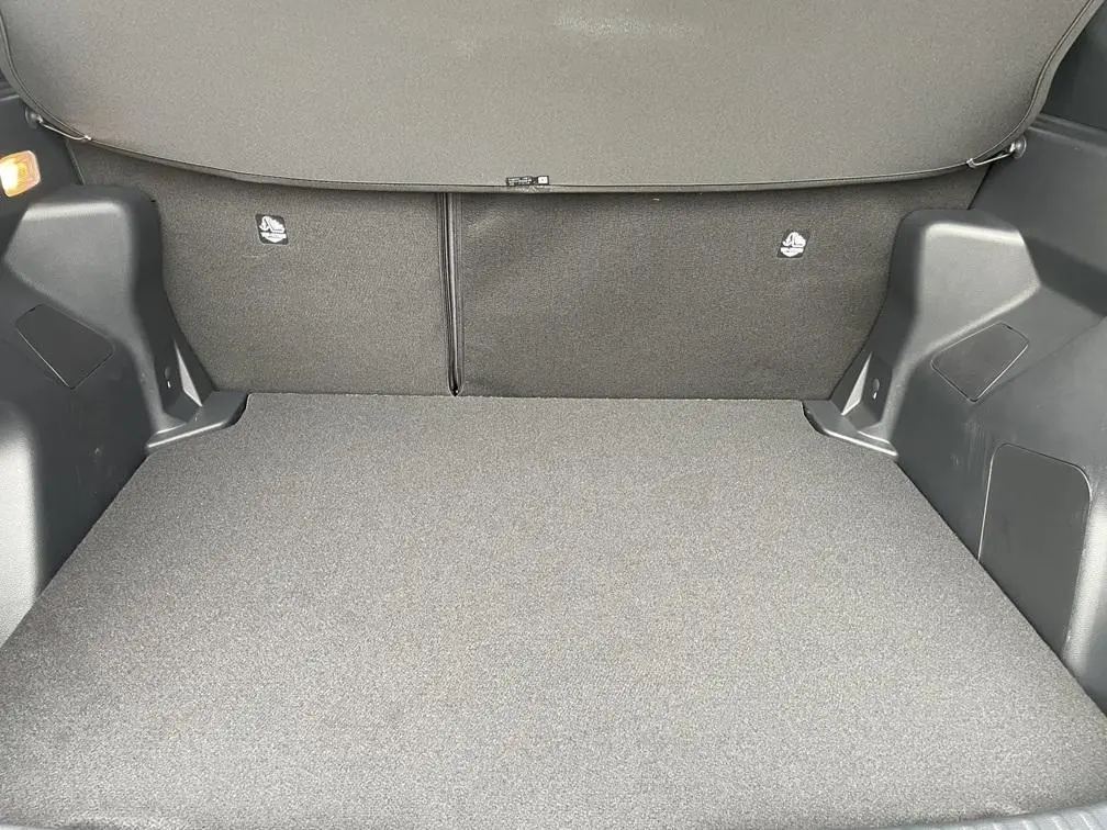 Coffre spacieux gris clair de la Toyota Yaris Cross 1.5 Hybrid 130h, vue intérieure arrière avec banquette rabattue.