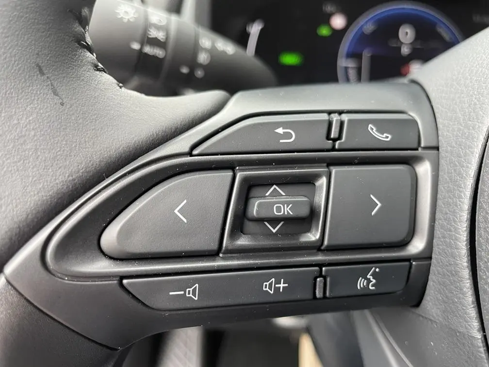 Gros plan sur les commandes multifonctions noires du volant côté gauche d'une Toyota Yaris Cross gris clair 2026.