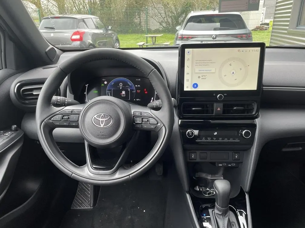 Vue intérieure avant de la Toyota Yaris Cross 2026, tableau de bord noir avec écran tactile central et volant multifonctions.