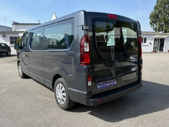 Vue 3/4 arrière droite d’un Renault Trafic Combi gris comète 2022, version 9 places avec vitres latérales teintées.